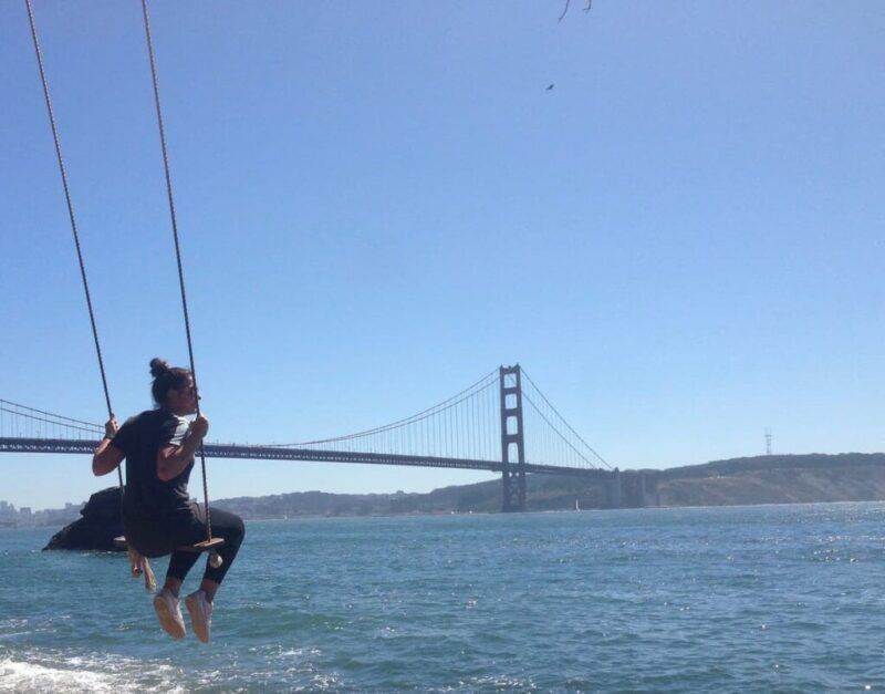 chica balanceandose en un columpio conpuente golden gate de san francisco al fondo