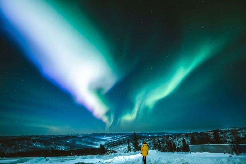aurora boreal en alaska, persona con chaqueta amarilla en primer plano