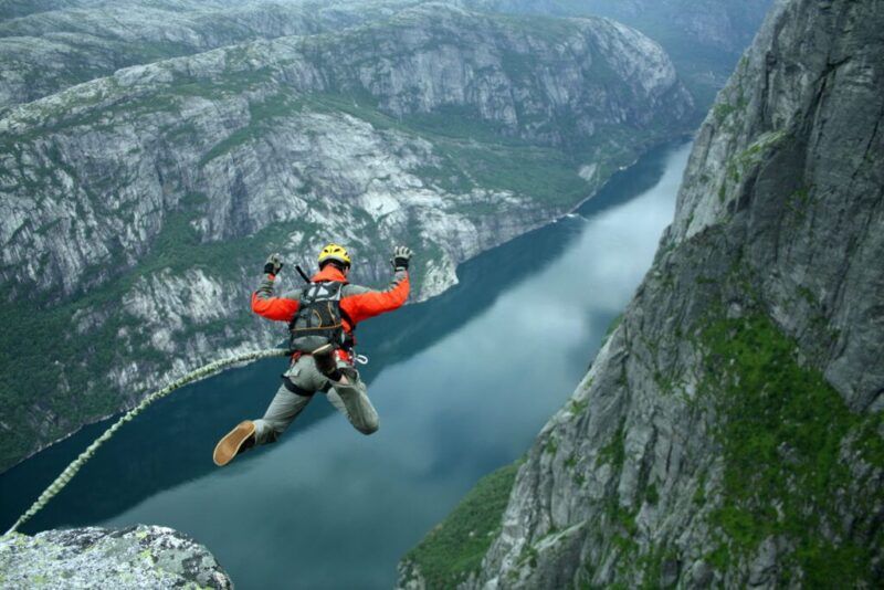 hombre saltando en bungee jumping en un paisaje de montañas y rio
