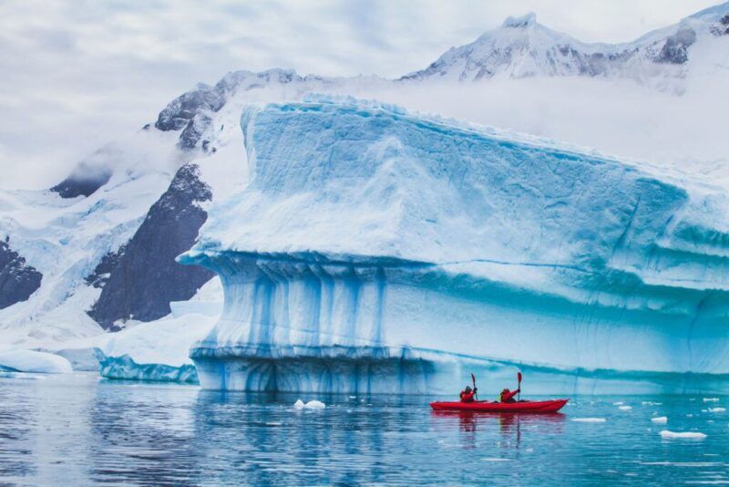 dos personas haciendo kayak entre bloquees de hielo en la antartida