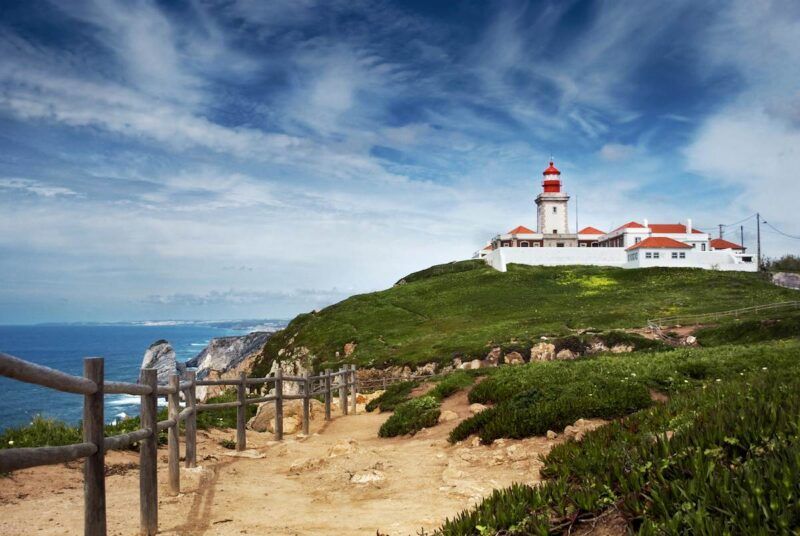 edificio blanco y rojo encima de un promontorio a orilla del mar en cabo de roca, portugal - weroad