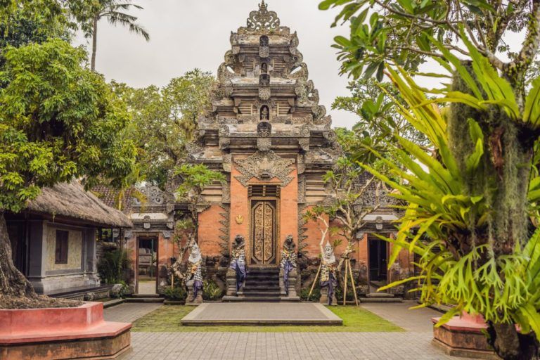entrada del palacio de puri saren en ubud, arboles y palmeras alrededor 