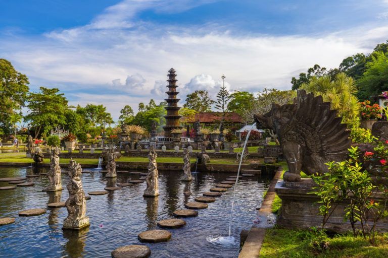 jardines del palacio de tirta gangga en bali con estatuas en las fuentes y vegetación alrededor