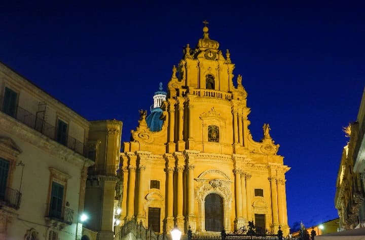 fachada del duomo de ragusa iluminada artificalmente, detrás cielo nocturno azul - weroad