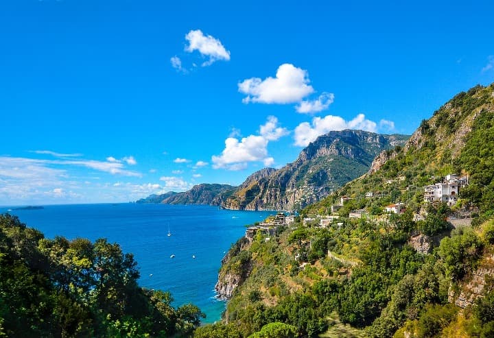 vista del mar desde la costa amalfitana en medio de montañas con vegetación y alguna pequeña casa - weroad