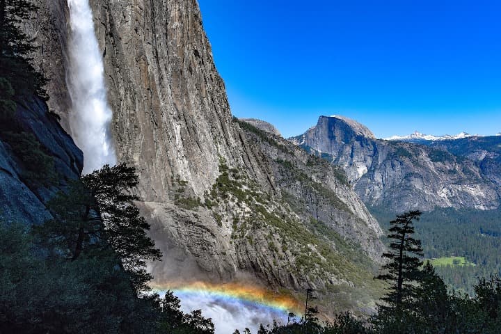 cataratas de yosemite, el agua forma al caer un arco iris, al fondo montañas - weroad