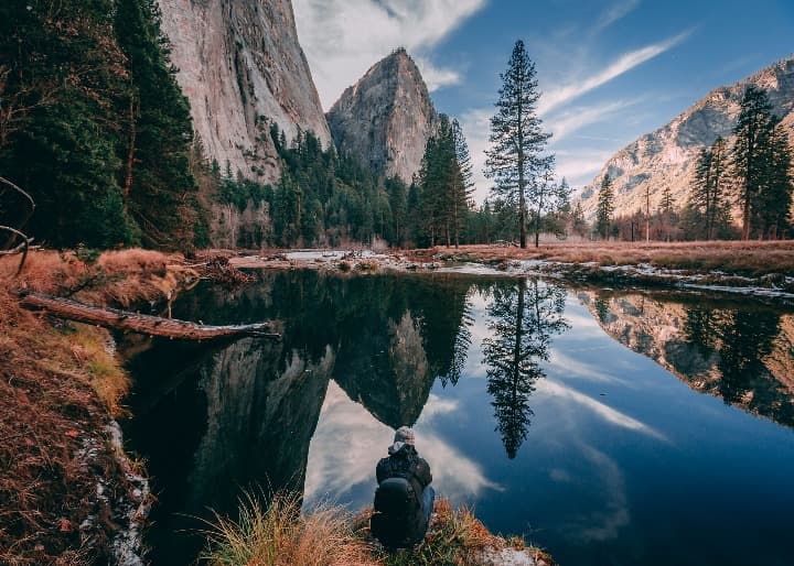 lago en primer plano que refleja montañas y arboles en segundo plano en el yosemite national park - weroad