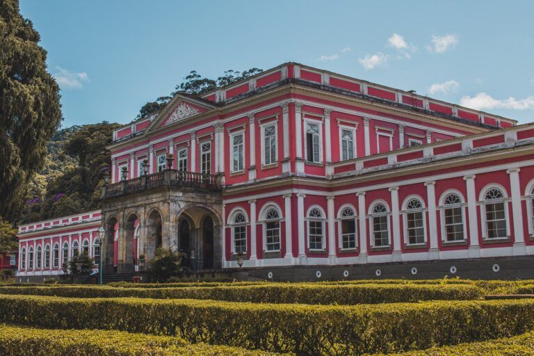 residencia de verano del emperador pedro II en petropolis, edificio bajo de color rojo y balnco con muchas ventanas, delante cesped - weroad