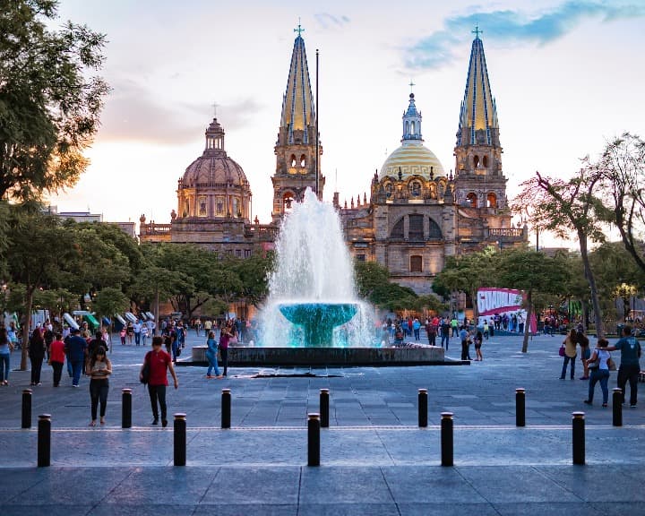 plaza de armas en guadalajara. gente que camina y una fuente, de fondo la catedral - weroad