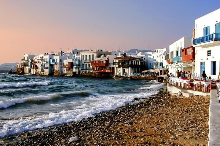 playa de mykonos, al fondo casas que dan al mar y mesas de un restaurante - weroad
