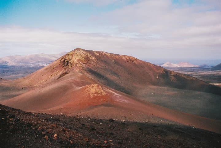 montaña en medio de un paisaje lunar en el parque nacional de timanfaya - weroad