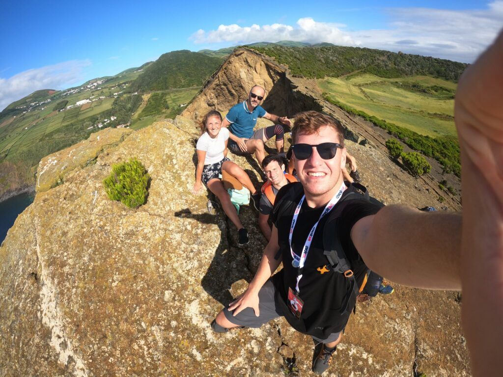 selfie de viajeros weroad en azores, subidos a un promontorio, detrás vegetación