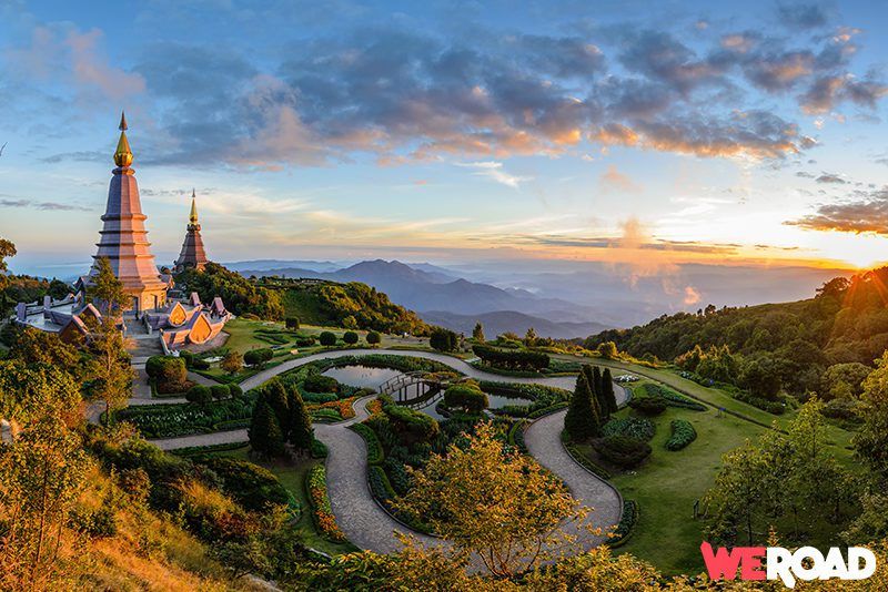 templo tailandés en medio de un parque con al fondo paisaje de montaña - weroad