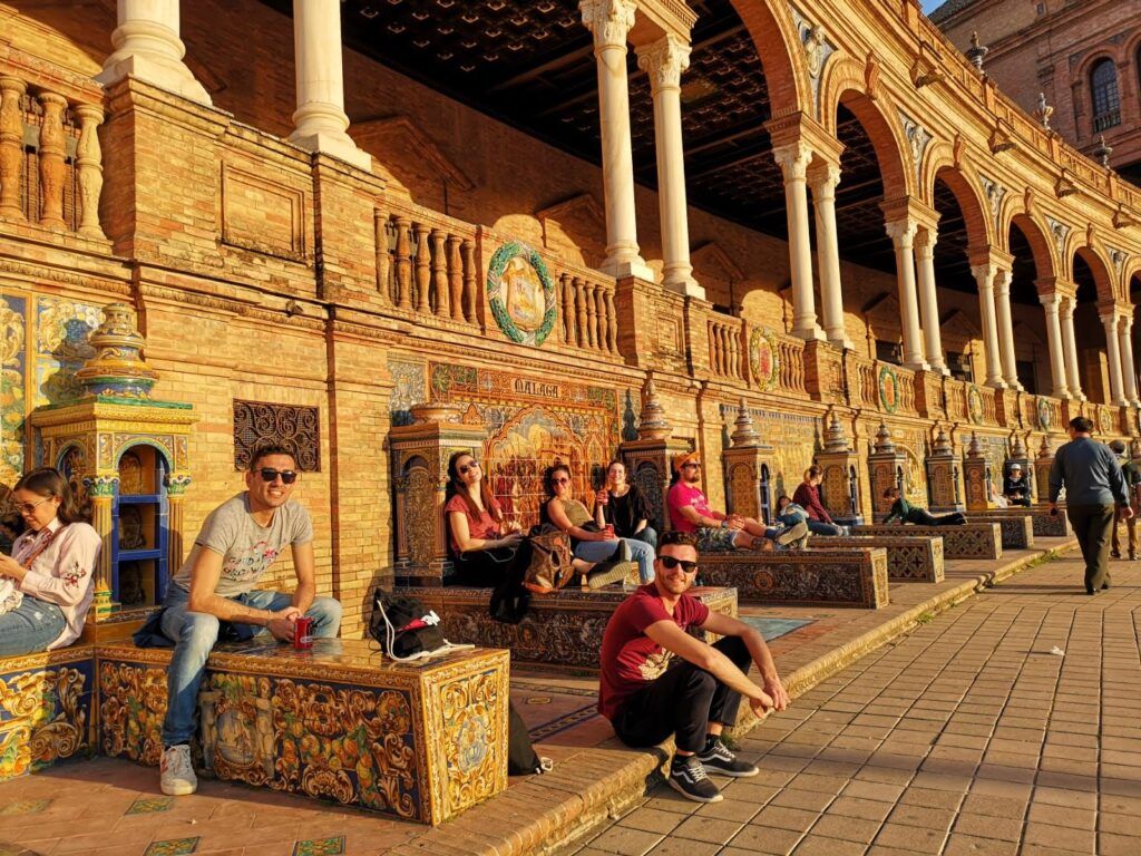 Viajeros de WeRoad descansando bajo el sol en la Plaza de España de Sevilla.