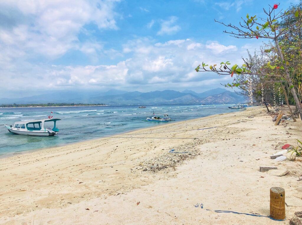 playa de gili air, indonesia. un barco en la orilla, mar y montañas al fondo