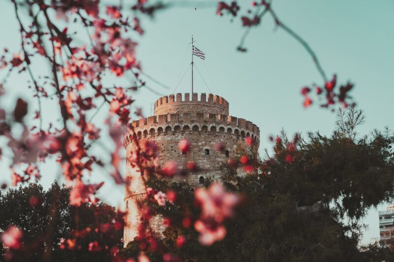 torre blanca de salónica, algo qué ver en grecia continental, vista desde detrás de unas ramas con flores de cerezo