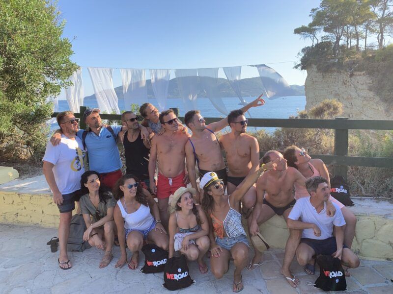 grupo de viajeros de weroad en zante, grecia mirando al lado derecho con detrás el mar