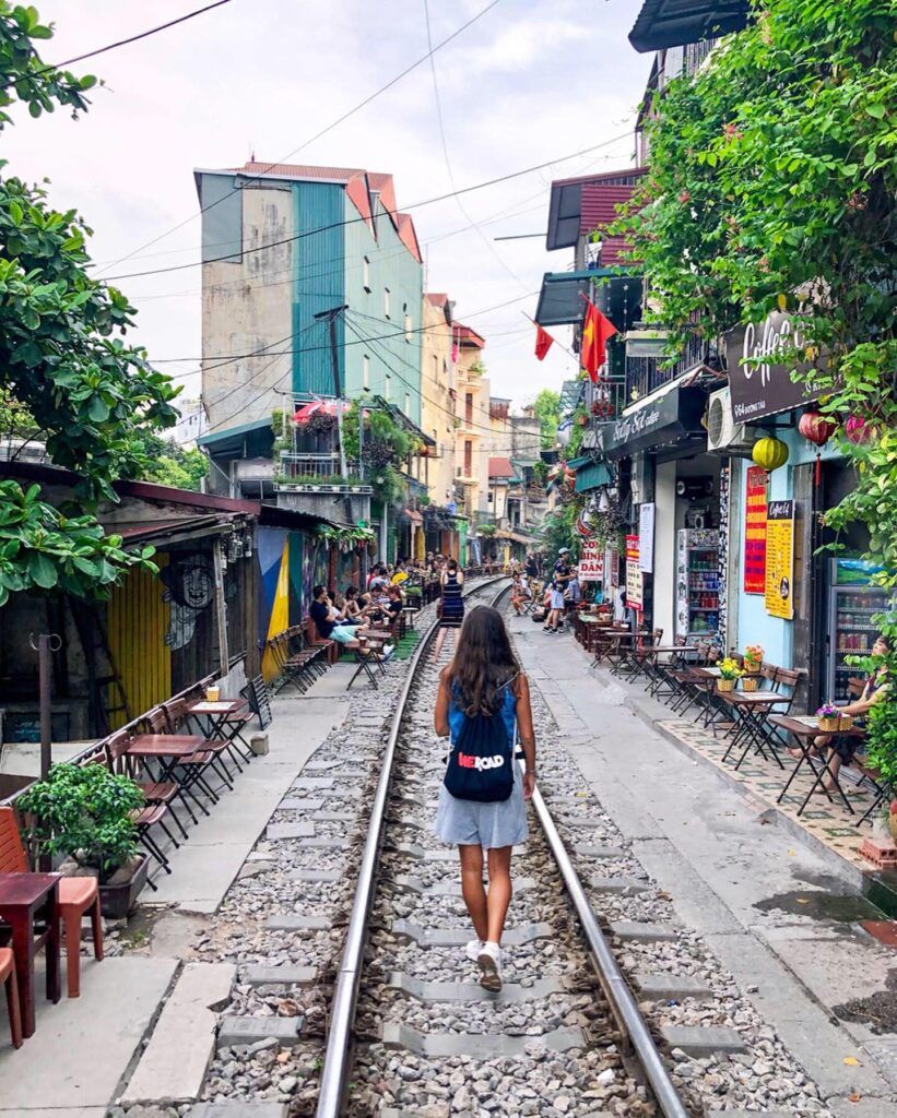 viajera weroad con su mochila, de espaldas, caminando en train street en hanoi, algo que ver en vietnam