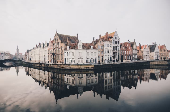 edificios de brujas reflejados en el agua de los canales - weroad
