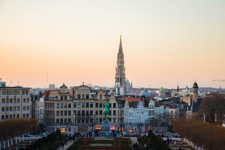 Vista del horizonte de Bruselas al atardecer, mostrando la torre del Ayuntamiento en el centro y el Jardín del Monte de las Artes en primer plano.