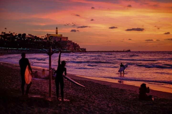 surferos en una playa de jaffa al atardecer, algo que ver en tel aviv - weroad
