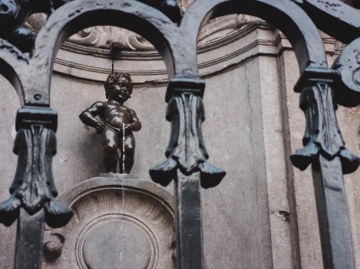 estatua del manneken pis detrás de una reja - weroad