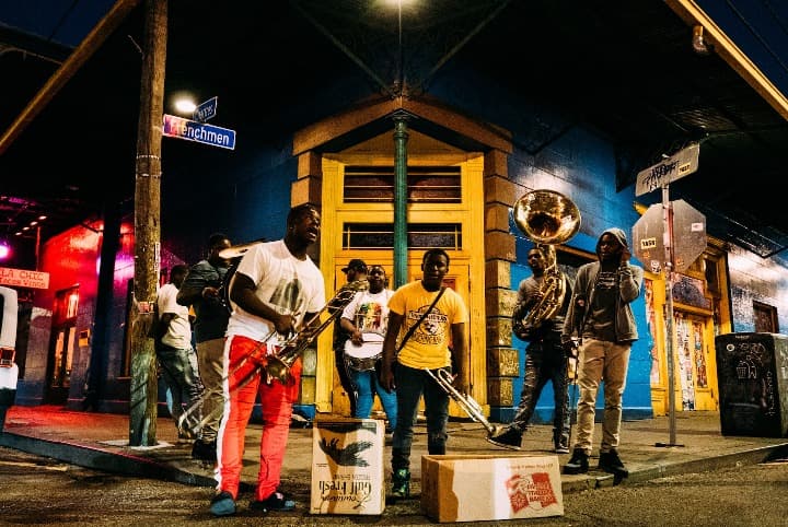 artistas callejeros tocando sus instrumentos y cantando en new orleans, a sus espaldas edificios coloridos - weroad