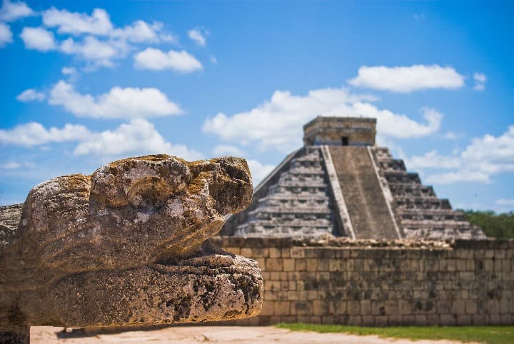 piramide de chichen itza y cabeza de dragón en piedra en primer plano, en méxico destindo donde ir en san valentin- weroad