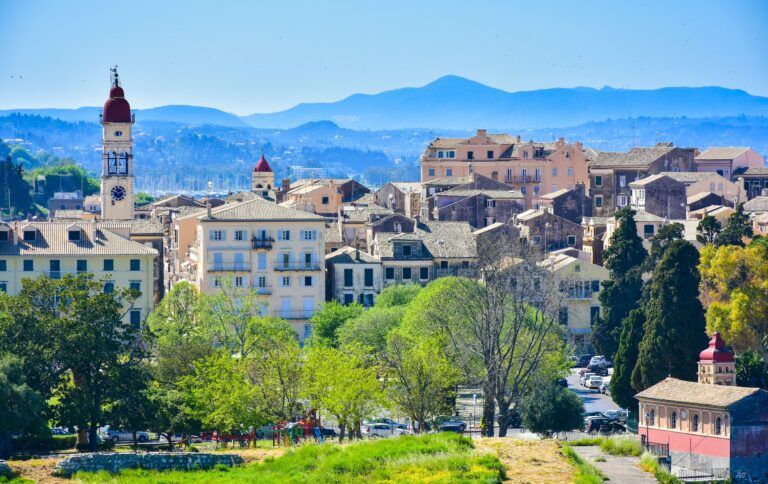 vista de la ciudad de corfu con edificios y al fondo montañas - weroad