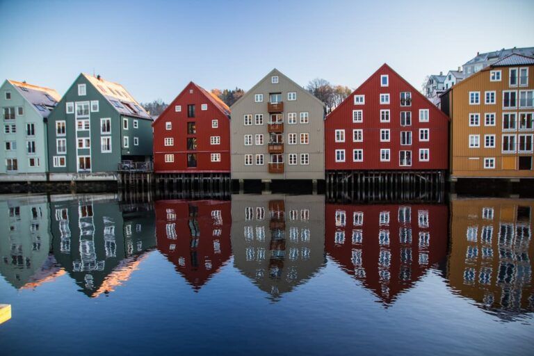 casas de colores reflejadas en el agua en trondheim - weroad