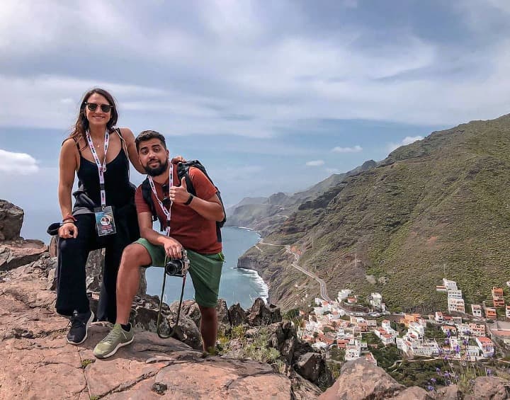 dos viajeros weroad en un paisaje de montaña, detrás mar y un pueblo de tenerife, una de las islas canarias que ver 
