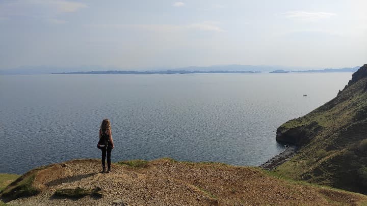 viajera weroad con mochila mirando al horizonte en un acantilado en escocia