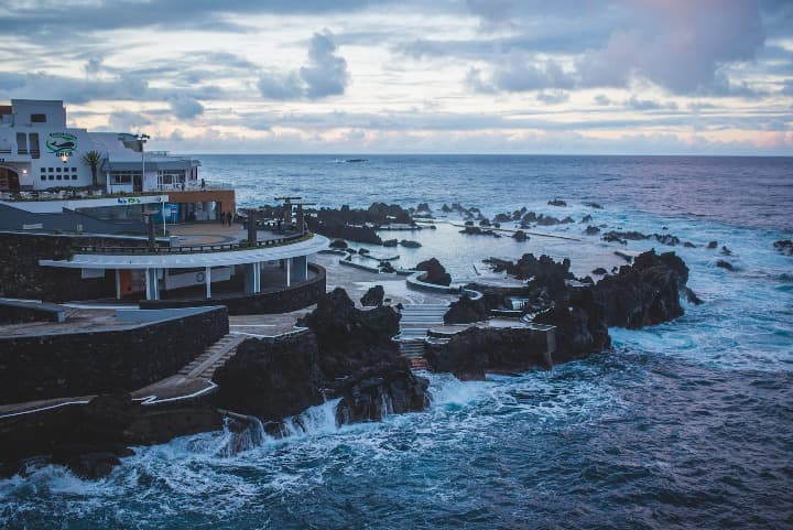 piscina natural con edificios delante y que se asoma al mar en porto moniz - weroad