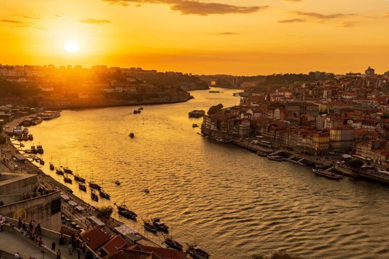 vista aerea del rio duero en oporto al atardecer, barcos y casitas en las orillas - weroad