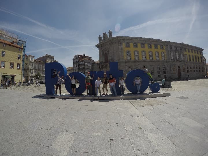 viajeros weroad delante de el letrero que pone: porto en una plaza de oporto