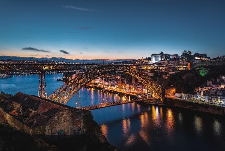 puente dom luis I al atardecer, edificios iluminados a los dos lados de rio duero - weroad