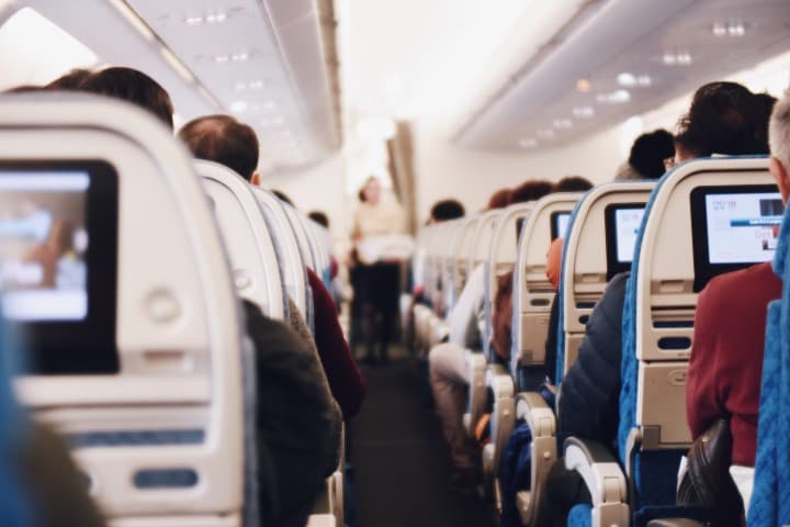 interior de cabina de avion, personas mirando pantallas y azafata al fondo desenfocada, alguien que puede ayudar si tienes miedo a volar - weroad