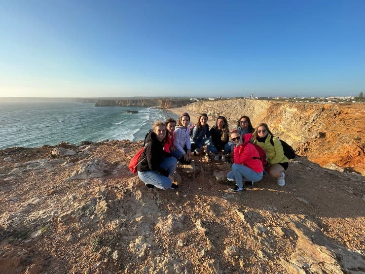 grupo de viajeros weroad en un acantilado en sagres, una de las payas de portugal, mar detrás