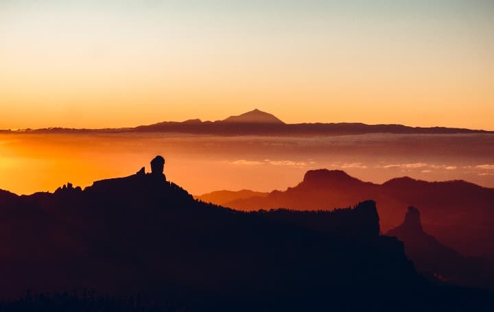 paisaje de montaña al amanecer, colores anaranjados. pico de las nieves, lugar donde hacer senderismo en canarias - weroad