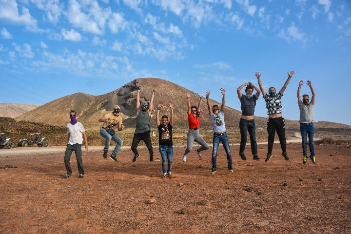 grupo de viajeros weroad saltando con detrás montaña en canarias