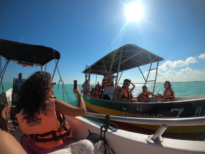 viajeros de weroad en dos lanchas en el mar de méxico, cada uno lleva chaleco salvavidas naranja