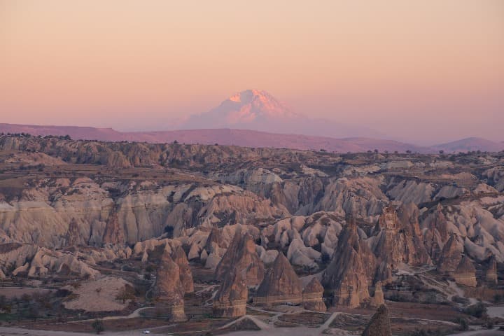 rocas en goreme, cielo rosado con al fondo una montaña - weroad