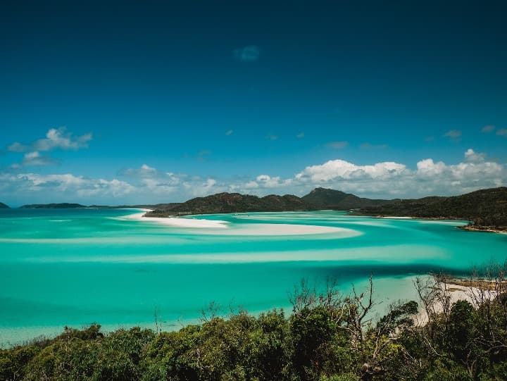 agua cristalian y montañas al fondo en una isla Whitsunday, australia - weroad