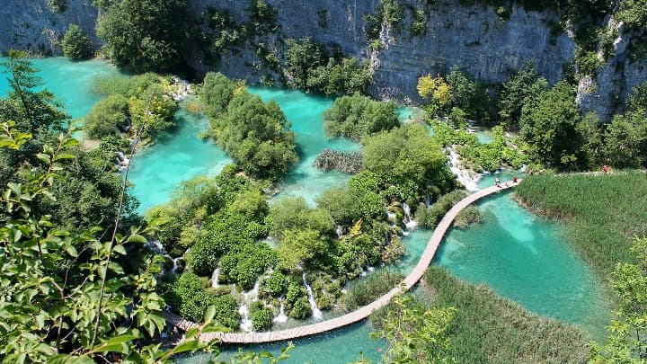 vista aerea de una zona del parque de plitvice con lago, arboles y una pasarela donde las personas pueden caminar - weroad