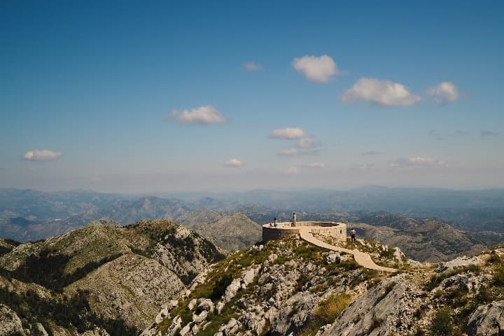 estructura redonda en piedra encima de monte lovcen, cielo con pocas nubes - weroad