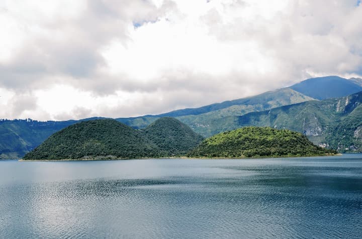laguna cuicocha. promontorios verdes, agua delante y cielo nublado - weroad