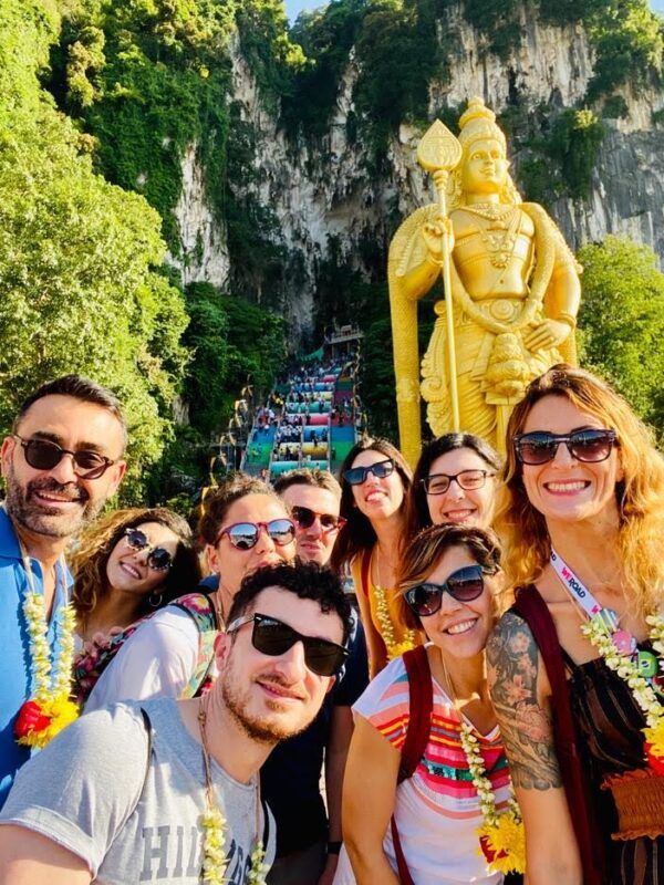 selfie de grupo de viajeros weroad delante de una estatua dorada en malasia