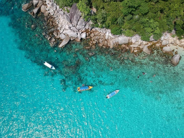 mar turquesa, 3 barcos y acantilado con arboles visto desde encima en las islas Perhentian, malasia - weroad
