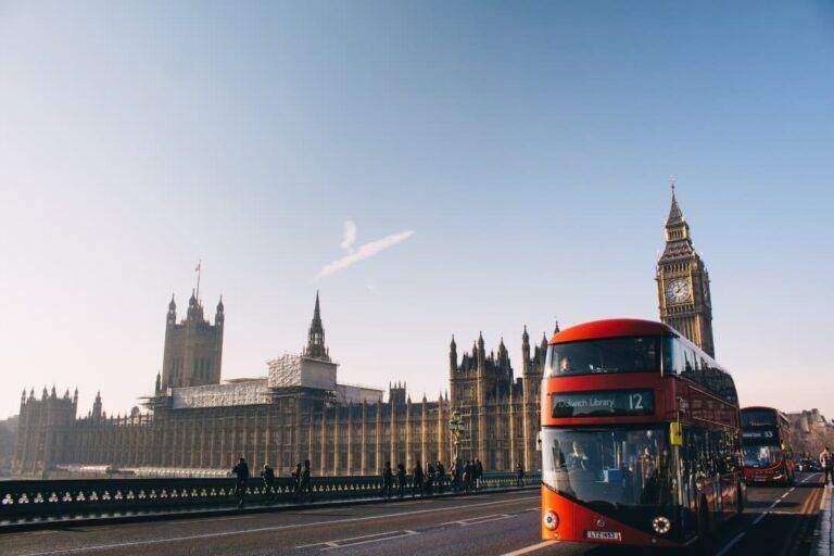 buckingam palace visto desde lejos con autobus rojo de dos pisos delante, algo que ver en londres