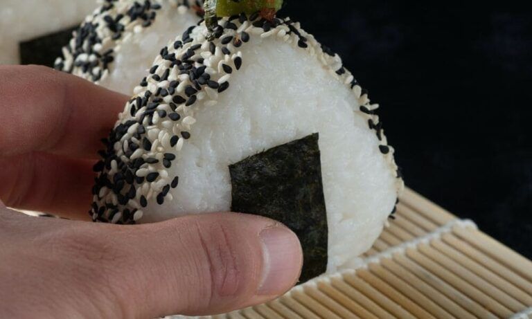 mano que coge un Onigiri, comida típica de japon - weroad